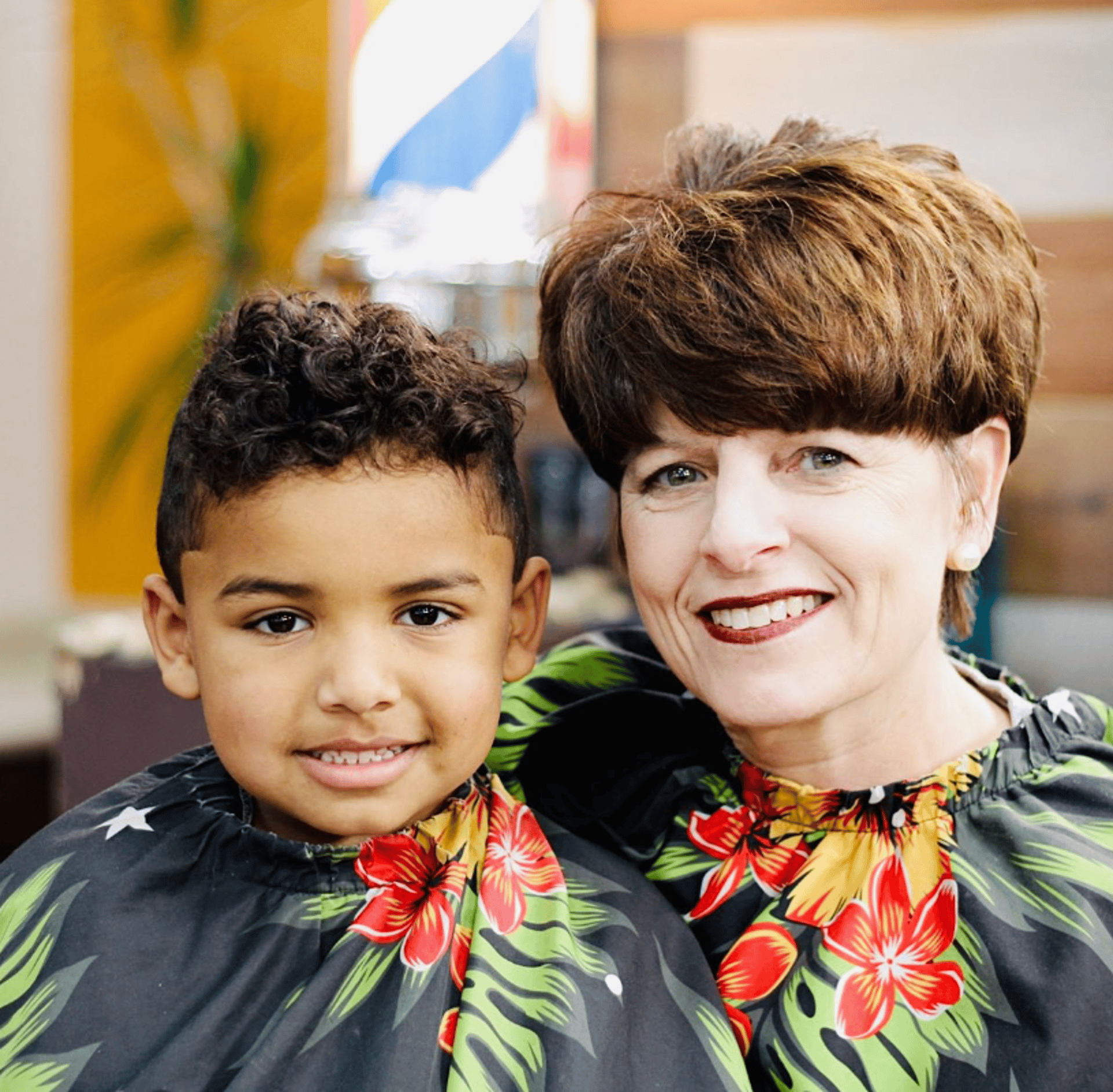 A mother and her son smiling after a haircut